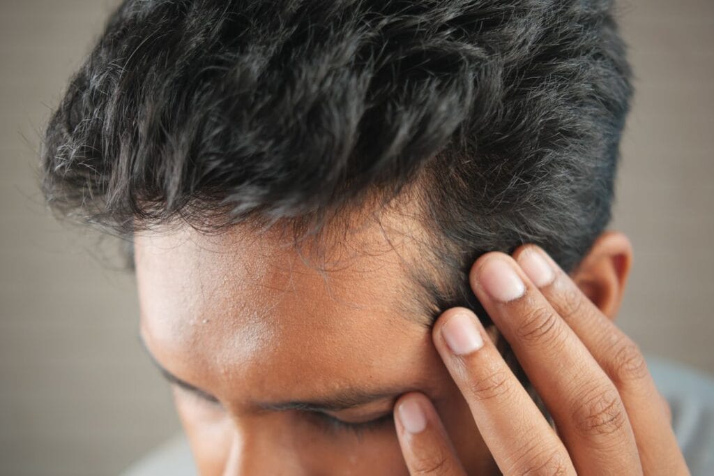 pexels-photo-12474260-12474260 Close-up of a man's hand touching his head in contemplation. Neutral tones and soft lighting.