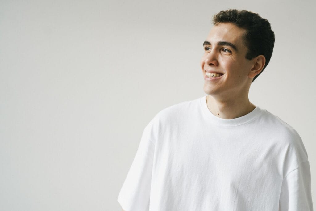 pexels-photo-9775441-9775441 Portrait of a happy man in a white t-shirt on a plain background, exuding positivity.
